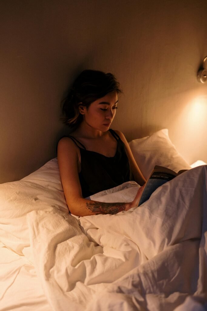 Frau sitzt im Bett und liest ein Buch vor dem Schlafen