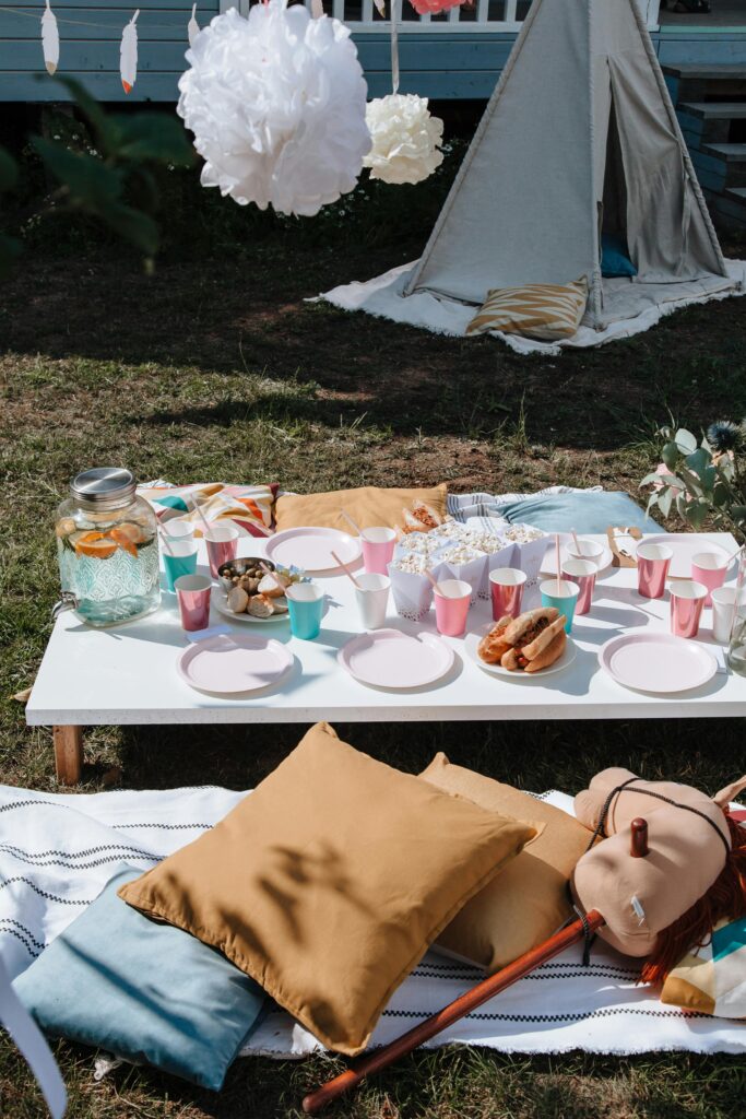 draußen ein niedriger Kindertisch mit Snacks und Getränken und gemütlichen Kissen sowie Tipi zum Zurückziehen