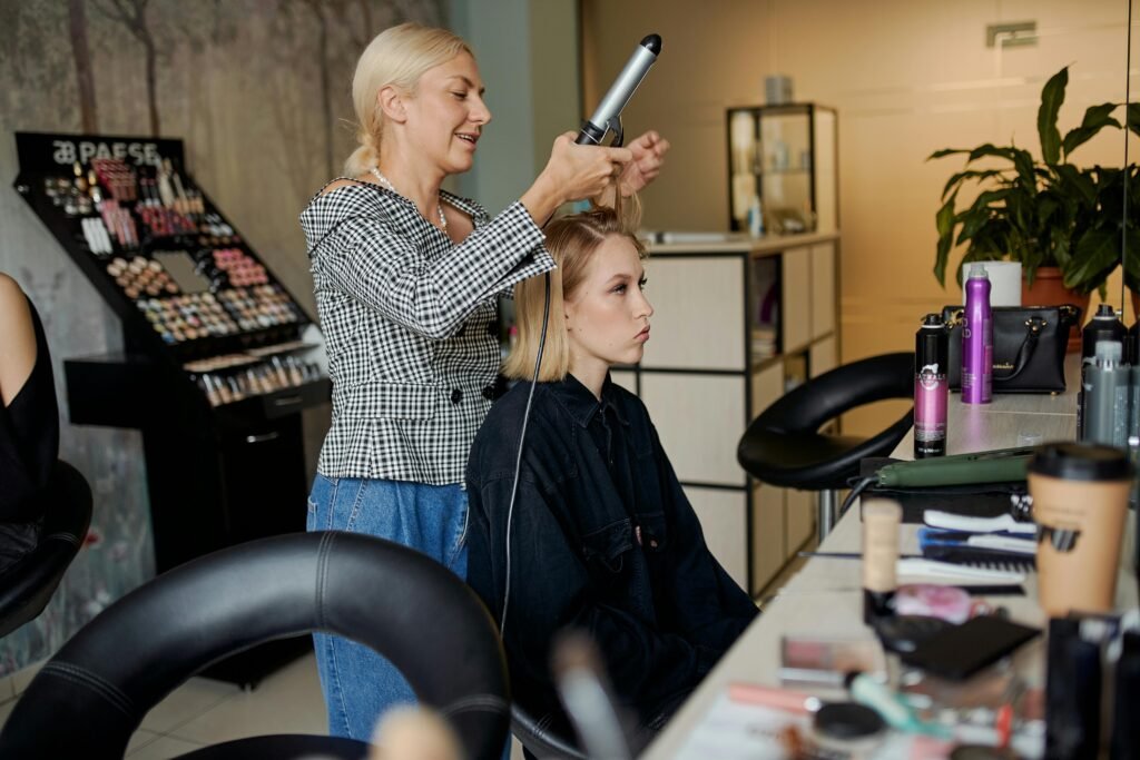 Friseurin arbeitet mit Frau im Salon und lacht