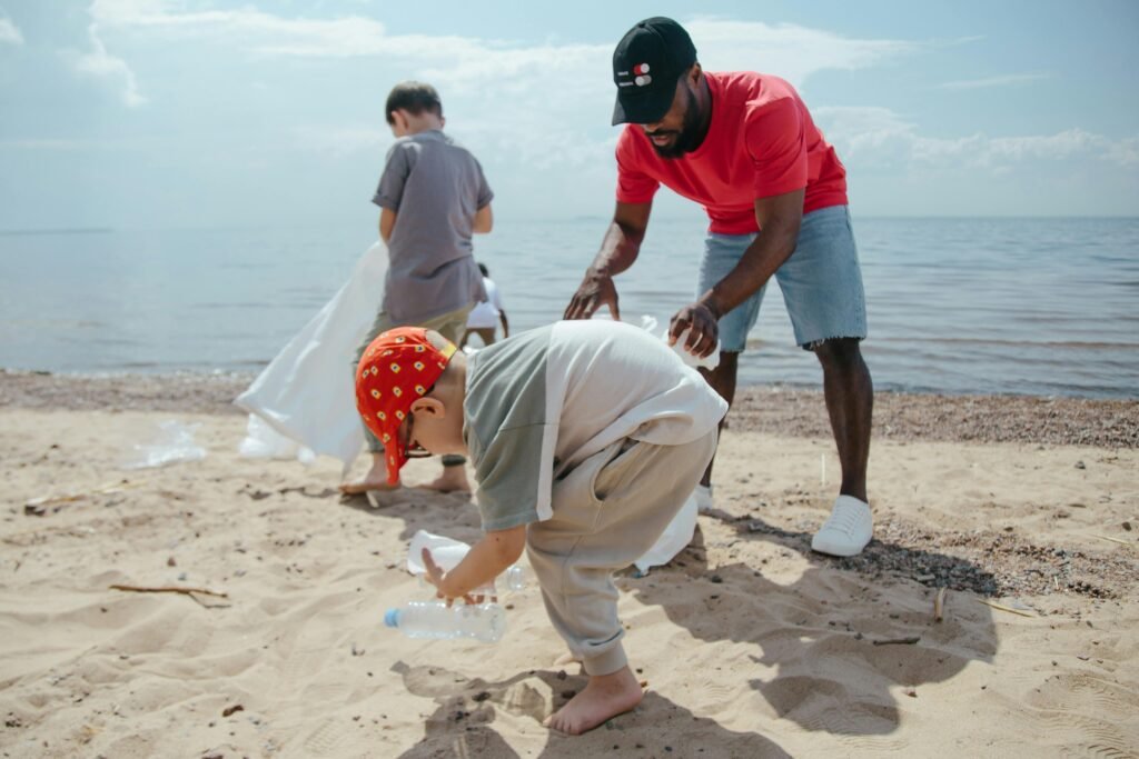 Erwachsener sammelt Müll mit Kindern am Strand